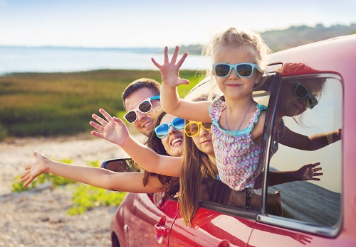 family in a car waving